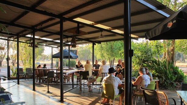 Un patio al aire libre con mesas y sillas, rodeado de follaje.