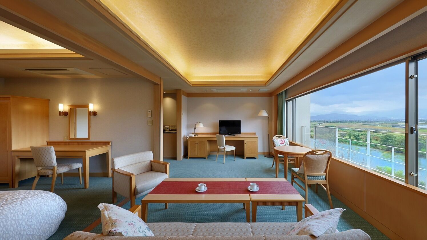 Une chambre d’hôtel équipée d’un lit, d’un bureau, d’une télévision, d’une table à manger et d’un balcon avec vue.