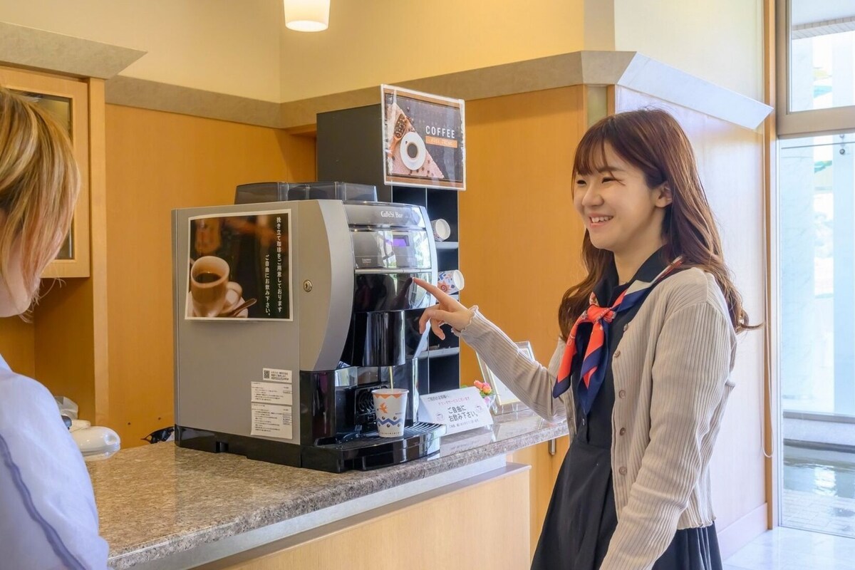 A coffee machine with a cup and saucer, a menu, and a sign above it.