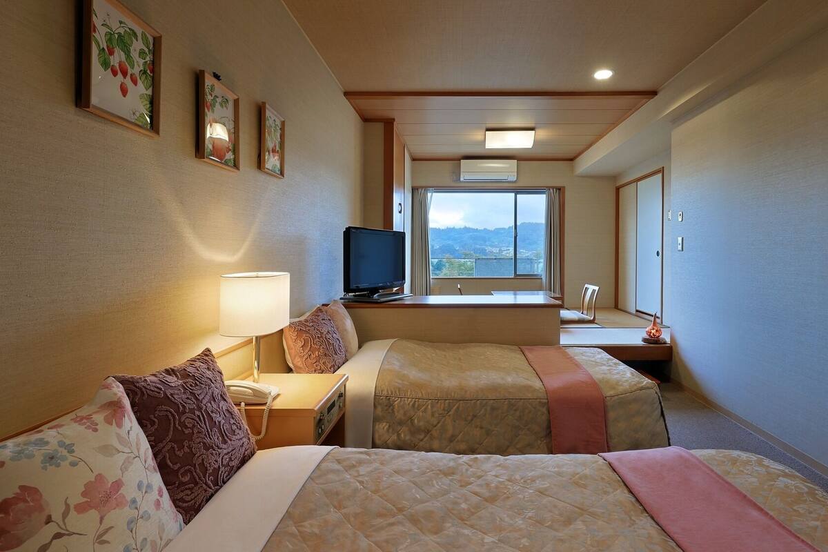 Una habitación de hotel con dos camas, televisión, escritorio y ventana con vistas.