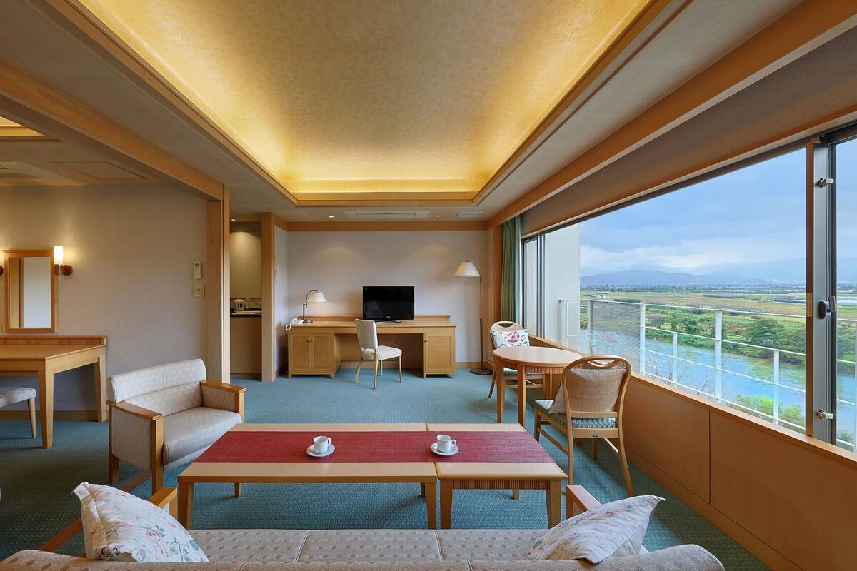 Habitación de hotel con cama, escritorio, televisor, sofá y balcón con vistas.