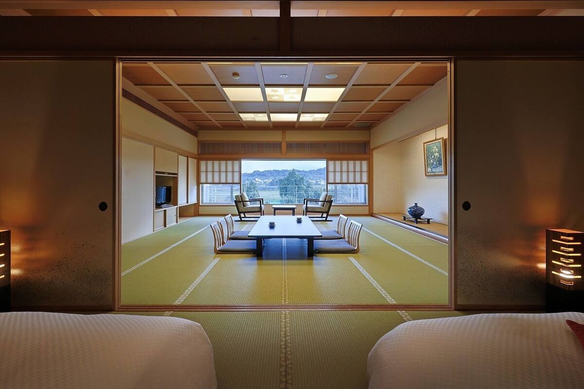 Una habitación tradicional japonesa con suelo de tatami, una mesa baja y dos sillas.
