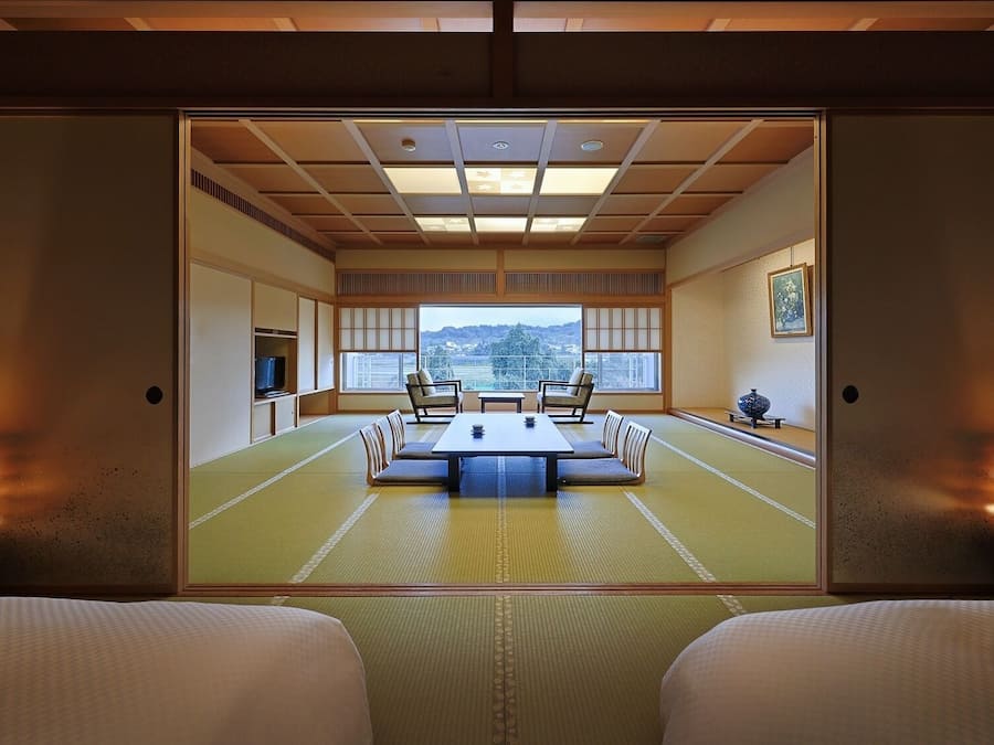 Une pièce de style japonais traditionnel, avec un sol recouvert de tatamis, une table basse et deux chaises.