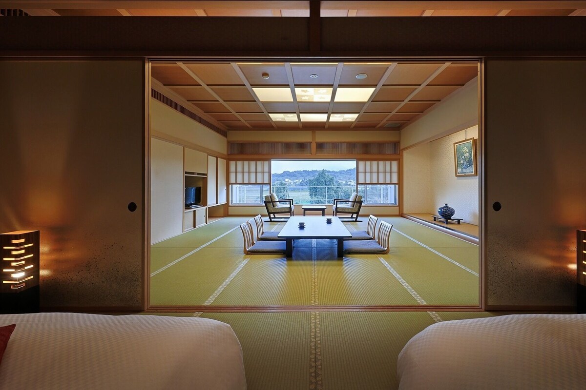 A traditional Japanese room with tatami flooring, a low table, and two chairs.