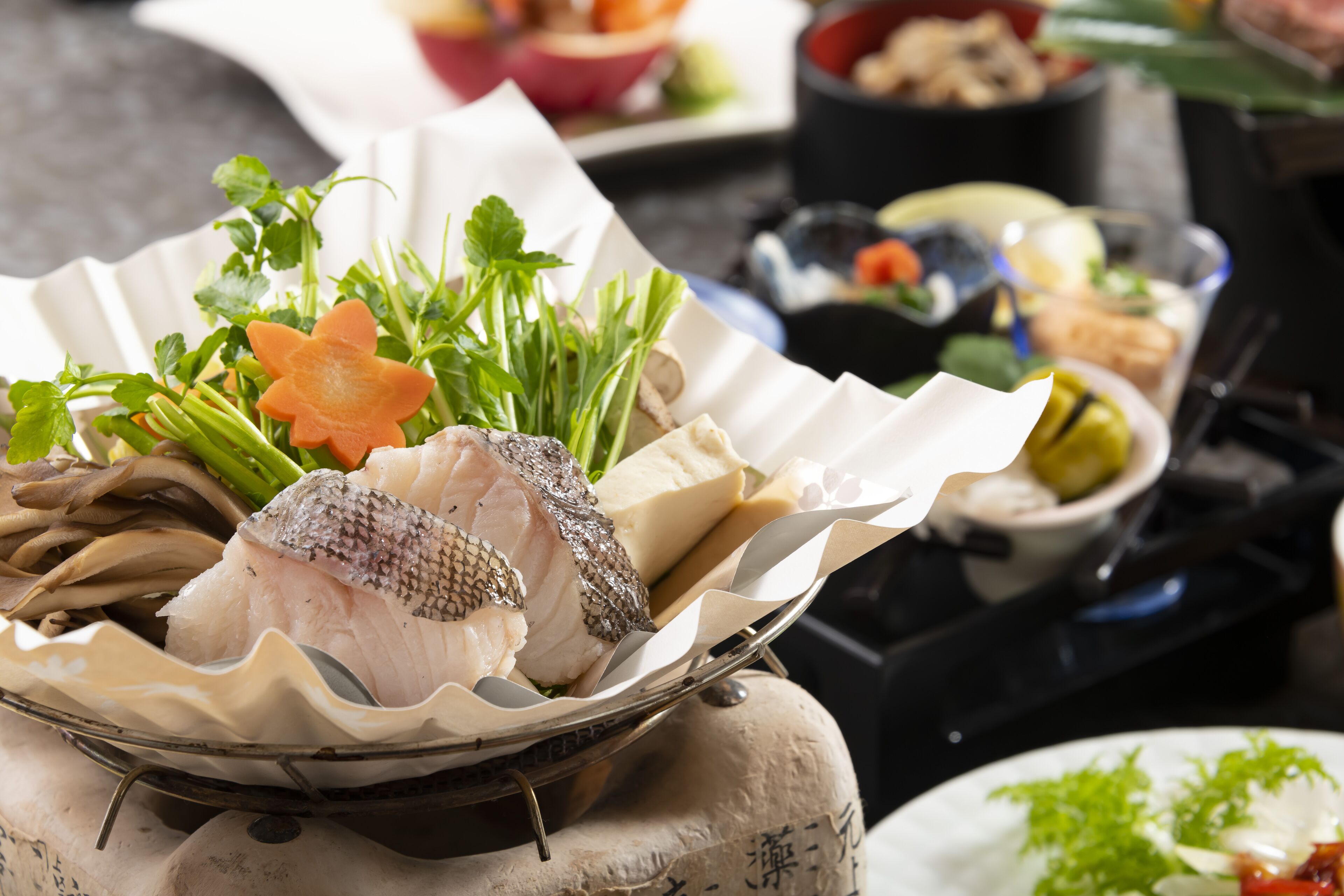 Ein Fischgericht mit verschiedenen Gemüsesorten und Kräutern, serviert auf einem traditionellen Keramikteller.