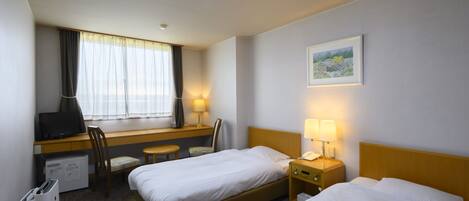 A hotel room with two beds, a desk with a chair, a TV, a lamp, and a picture on the wall.
