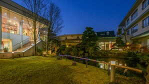 A courtyard with a modern building, a small pond, and a pathway. - Hotel Symphony (Sagae)