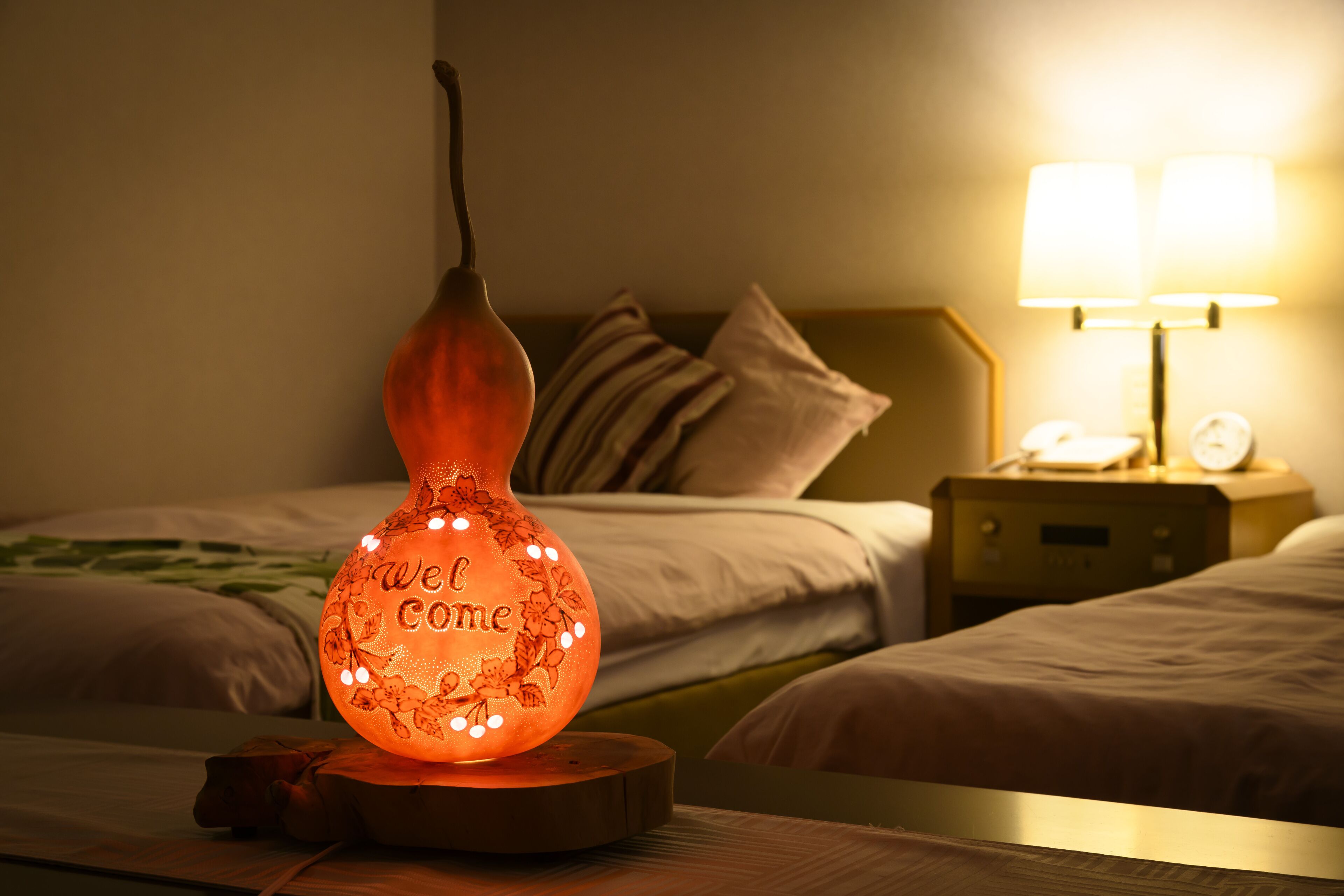 A bed with a bedside table, a nightstand with a lamp, and a decorative light fixture.