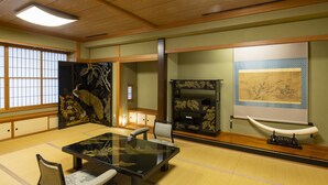 A traditional Japanese room with tatami flooring, a low table, chairs, and a sliding door. - Hotel Symphony (Sagae)