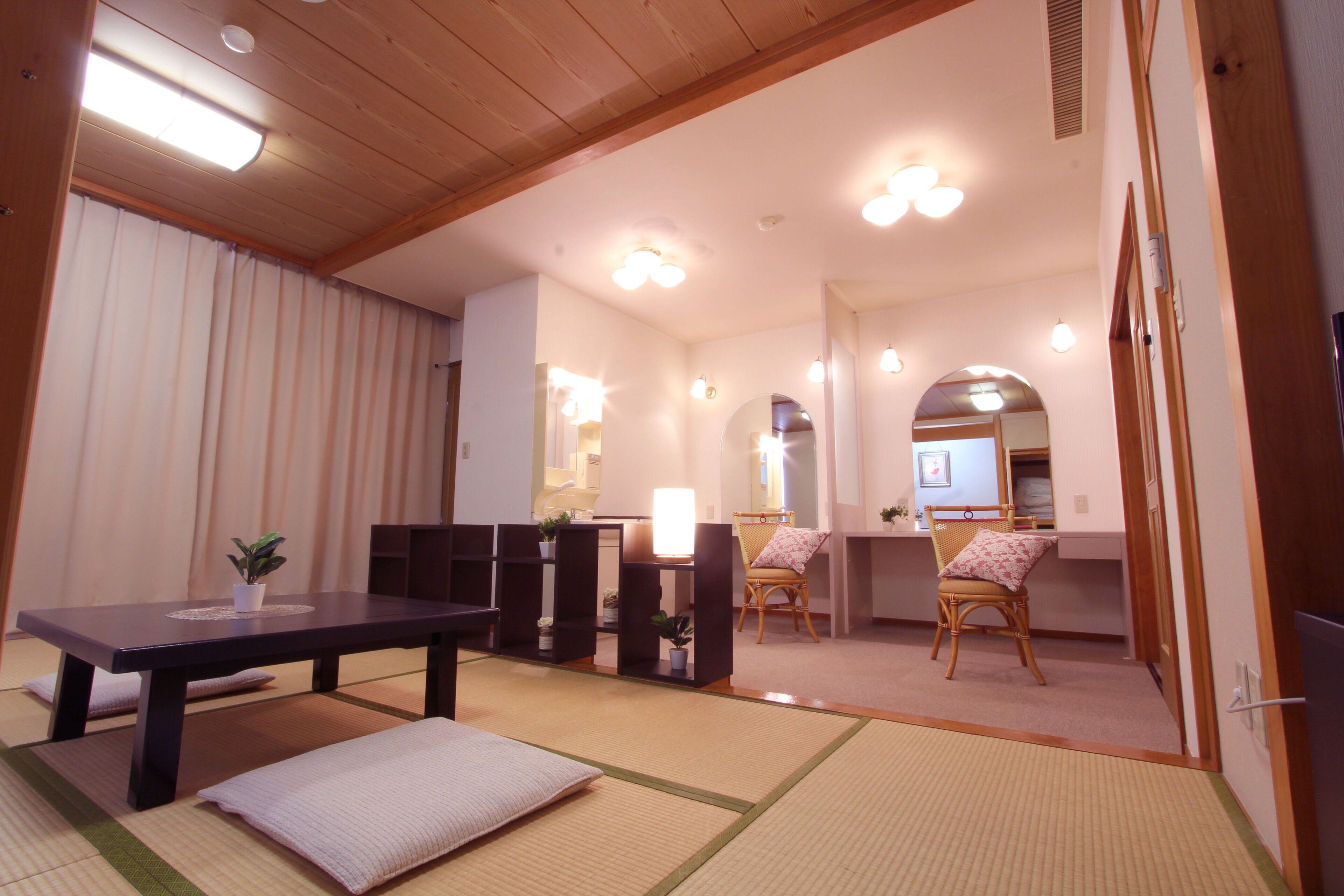 A traditional Japanese room with tatami flooring, a low table, and two chairs.