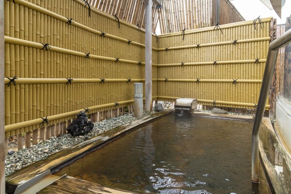 A traditional Japanese onsen with bamboo walls, a stone pathway, and a small water channel. - Hotel Symphony (Sagae)