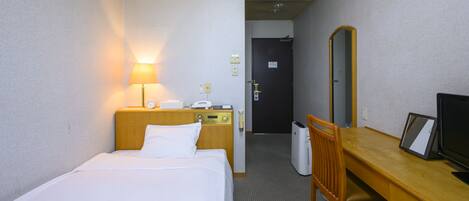 A hotel room with a bed, bedside table, lamp, desk with a chair, television, and a mirror.