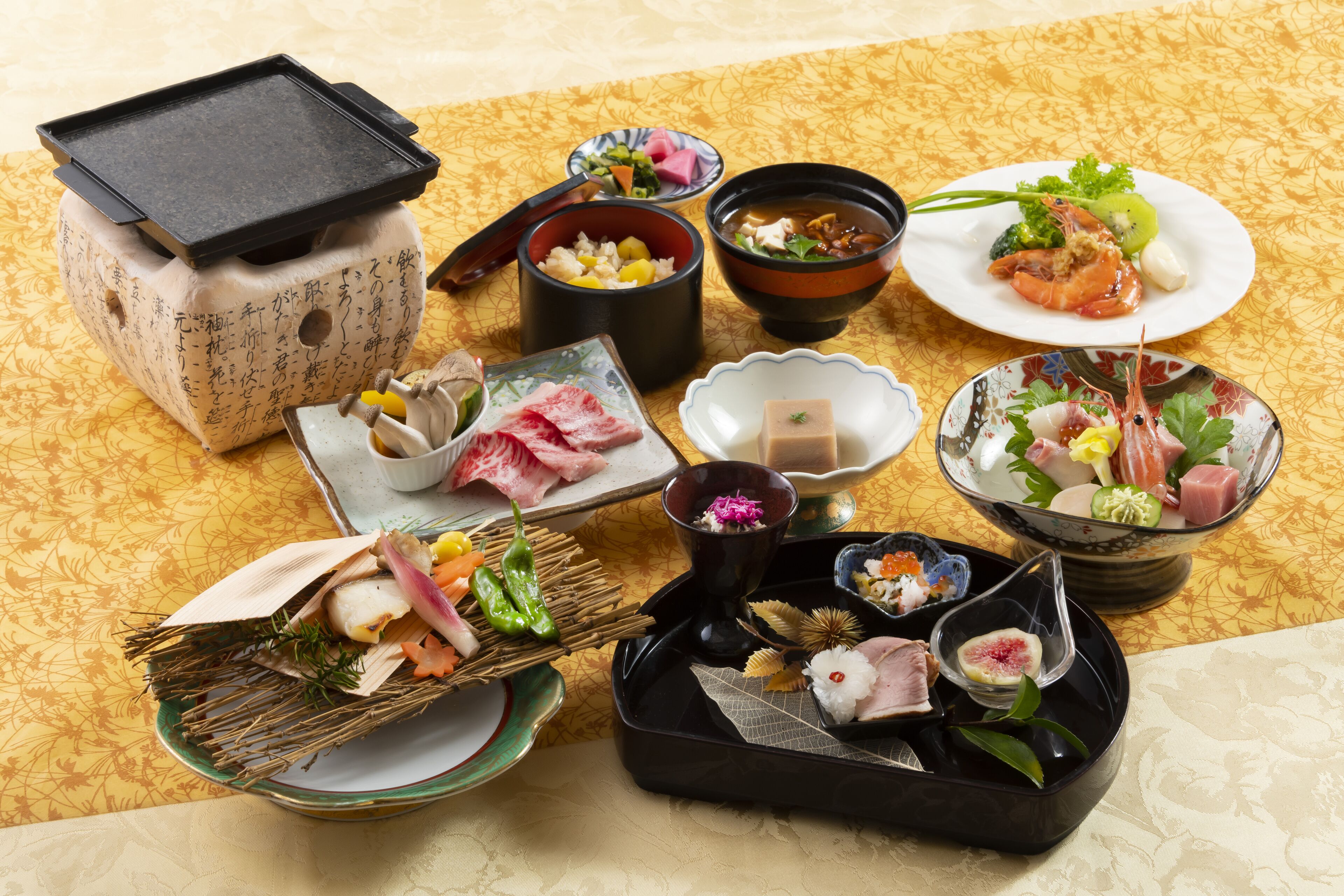 Une variété de plats japonais disposés sur une table recouverte d’une nappe à motifs.
