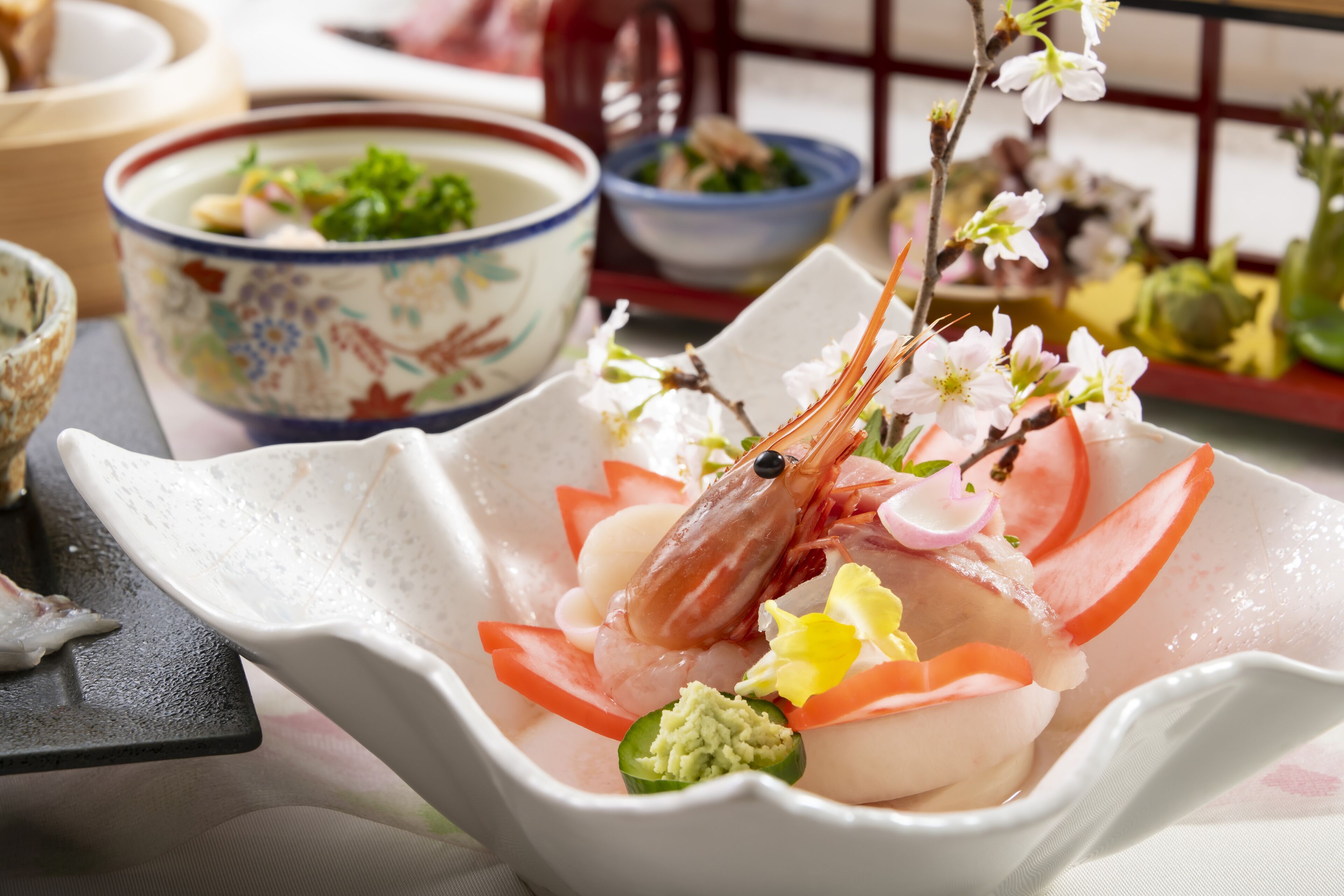Un bol de sashimi garni de crevettes, de poisson et d’autres accompagnements, entouré d’autres plats et d’autres bols.