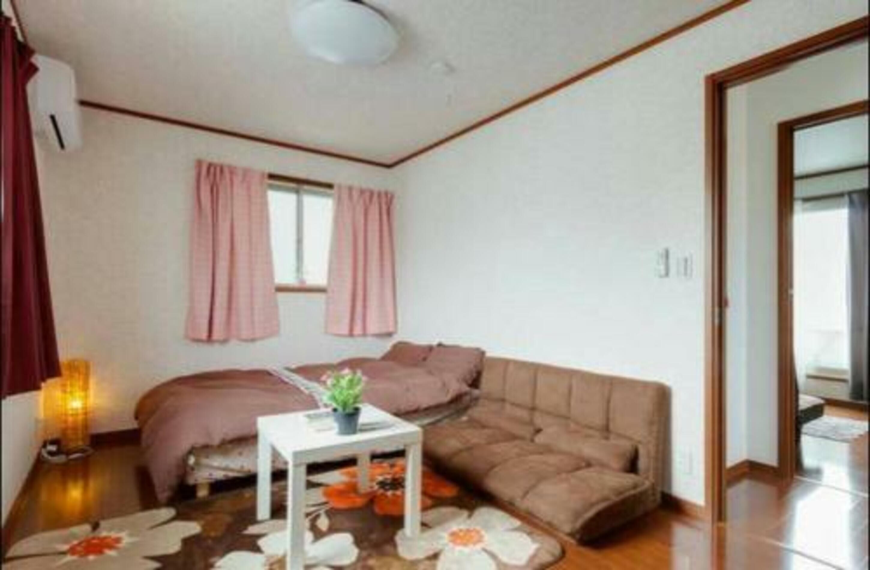 A cozy room with a bed, a sofa, a small table with a plant, and a window with curtains.