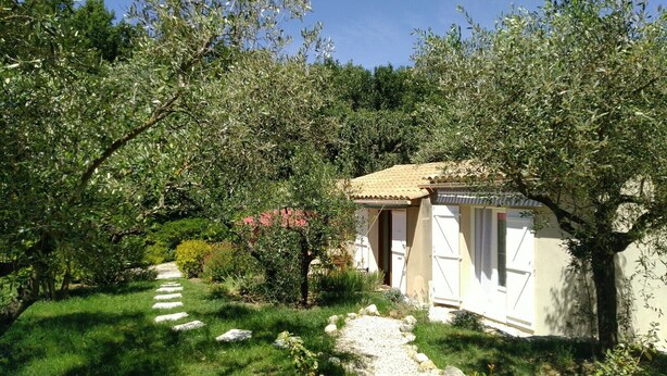 A rustic cottage with a stone pathway leading to a white door, surrounded by lush greenery and olive trees. - Lovely Mazet with shared, heated, secure swimming pool (Mirabel-aux-Baronnies)