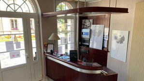 A reception desk with a wooden counter, a lamp, framed artwork, and a chalkboard menu.