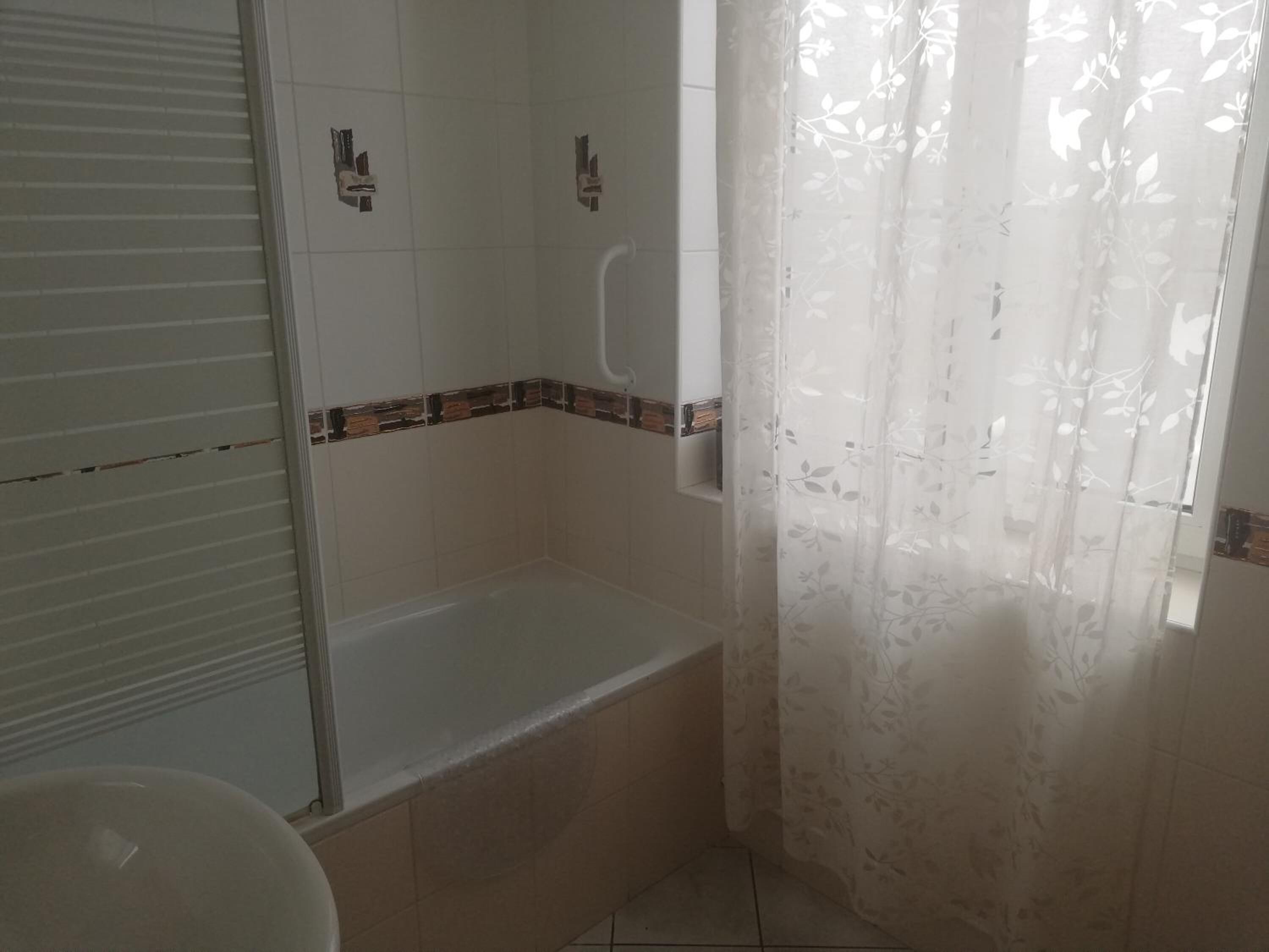 A bathroom with a bathtub, a toilet, and a shower area.