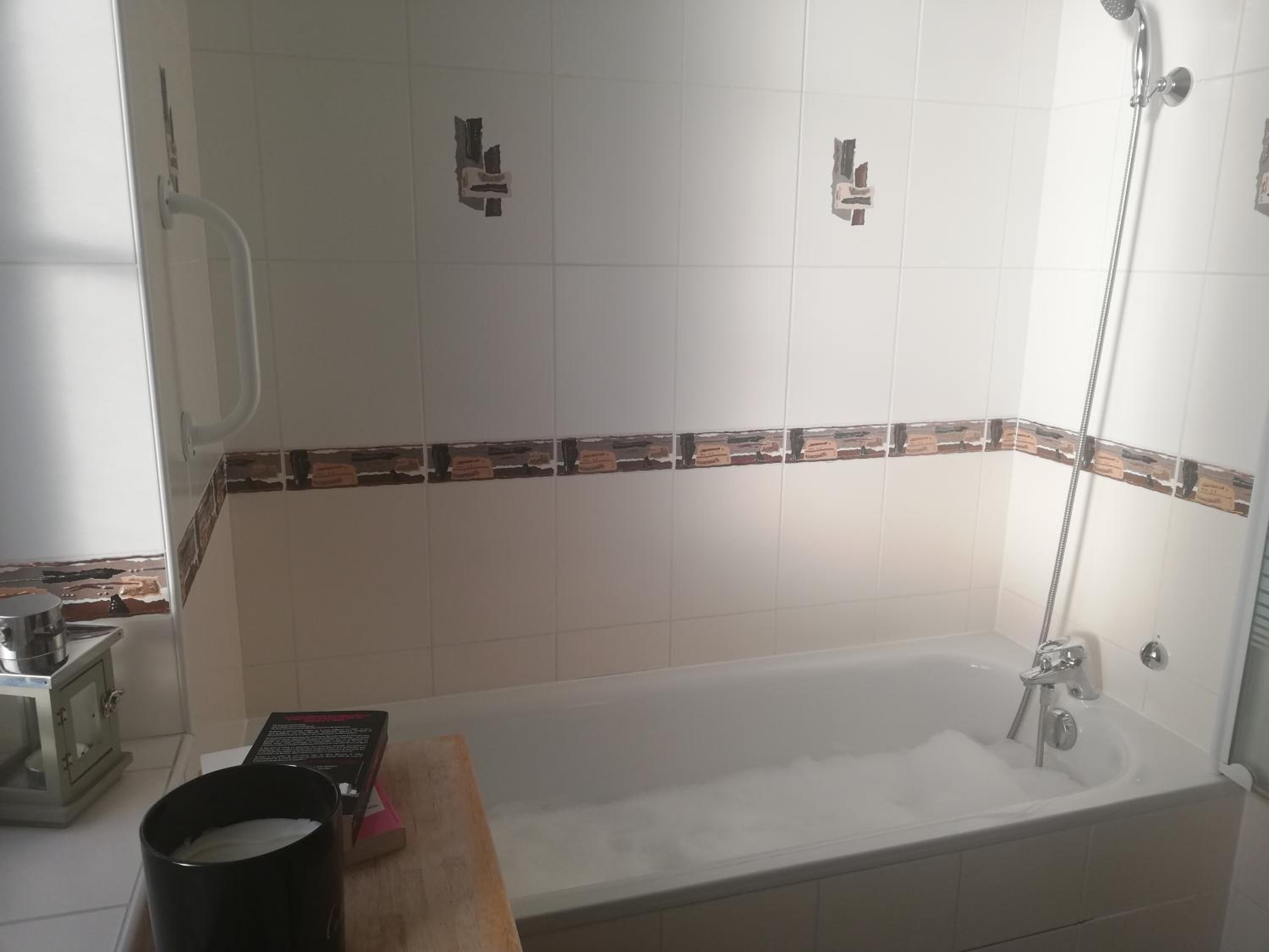 Une salle de bain avec une baignoire, une douche et un petit lavabo.