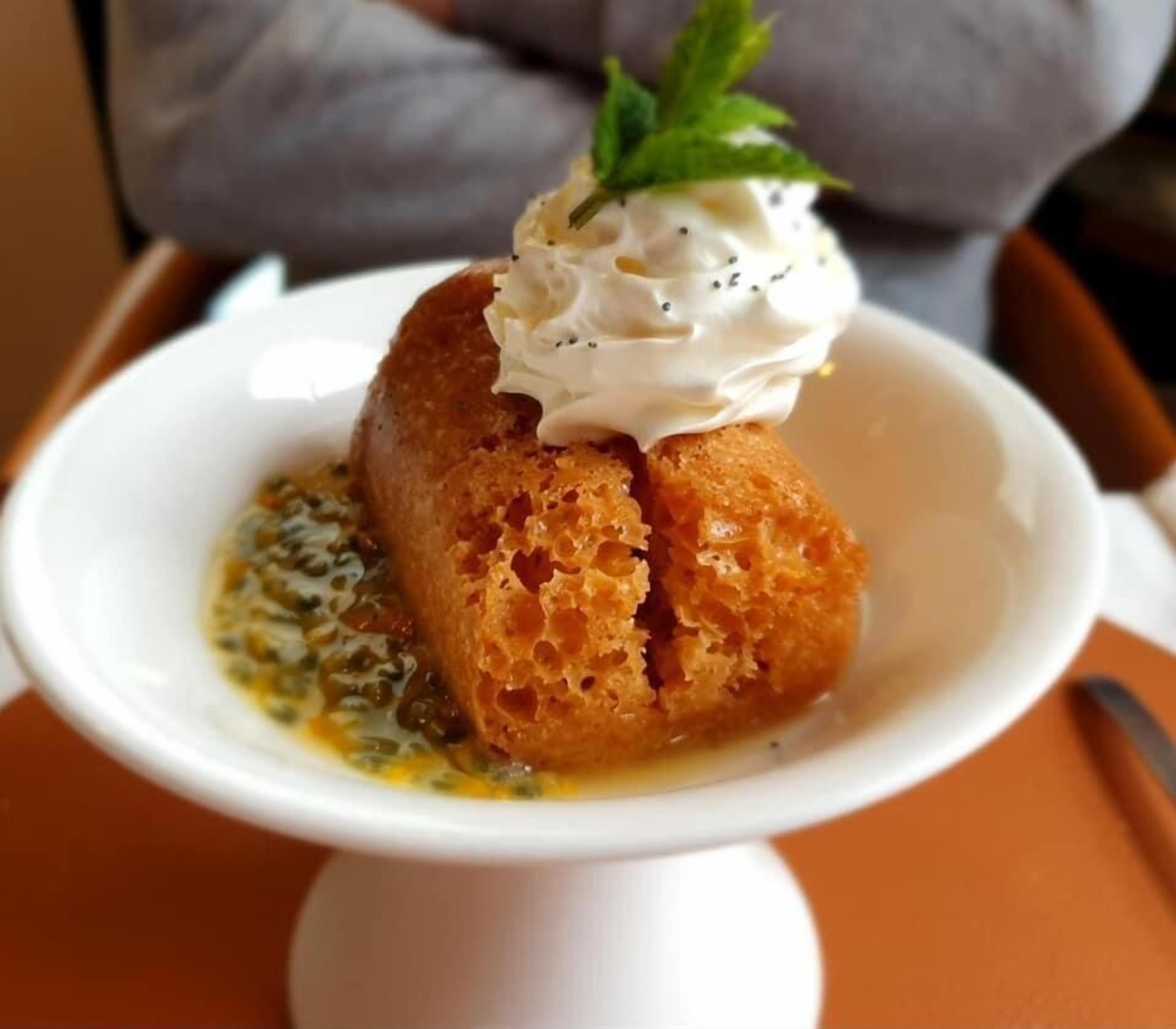 Un postre sobre un plato blanco, con guarnición, servido en un pedestal blanco.
