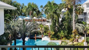 Een resort met een zwembad, omgeven door palmbomen en uitzicht op de oceaan.