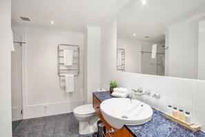 A modern bathroom with a white toilet, a sink with a marble countertop, and a glass shower enclosure. - Belle Escapes - Oceanview Suite Alamanda Beachfront Resort "88" (Palm Cove)
