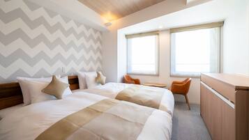 A hotel room with two beds, a desk, and a chair.