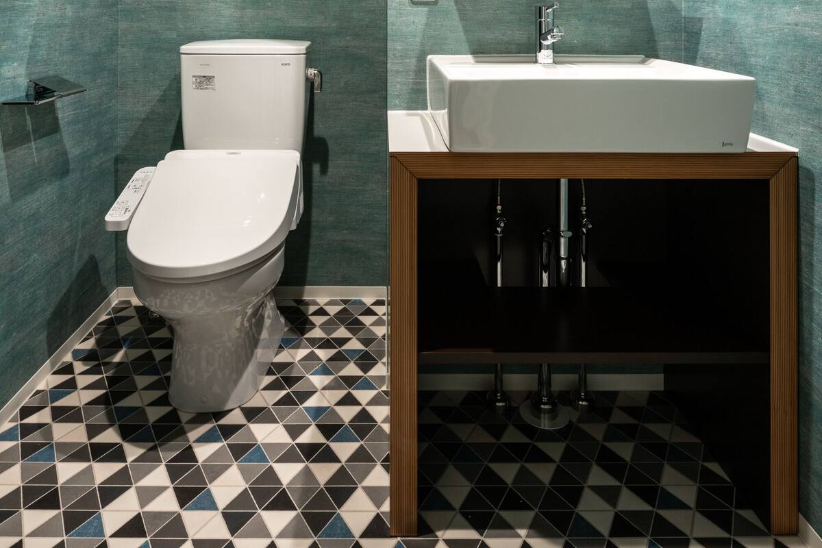 A bathroom with a toilet, sink, and mirror.