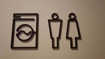 A restroom sign with a handwashing symbol and a urinal symbol.