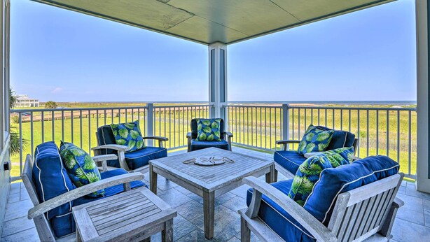 A covered patio with outdoor furniture and a view of the landscape. - Gulf View + Beach Access: Galveston Resort Condo! (Galveston)