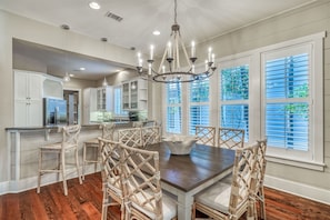 Enjoy a casual dining experience at this kitchen with a central island, refrigerator, and coffee machine, surrounded by a dining table and chairs.