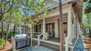 A covered outdoor area with a grill, seating, and steps leading to a door. - Charming Cottage in WaterColor, Beach Club Access, Bikes. Open Layout, Steps to Seaside. Book Now! (Santa Rosa Beach)