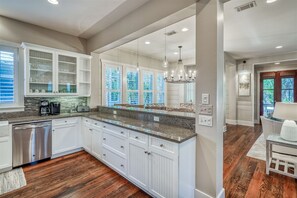 Enjoy meals in this well-equipped kitchen with a dishwasher, stainless steel refrigerator, and large window offering a view of the outdoors.