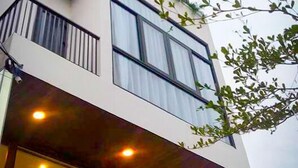 A modern multi-story building with balconies, large windows, and a tree in the foreground. - Crystal Le Apartment Danang (Da Nang)