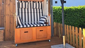 A wooden deck with a striped outdoor seating area, a metal umbrella, and a stone base. - Welcome to the beautiful 3 rivers city with Andrea and Axel <br> (Hann. Münden)