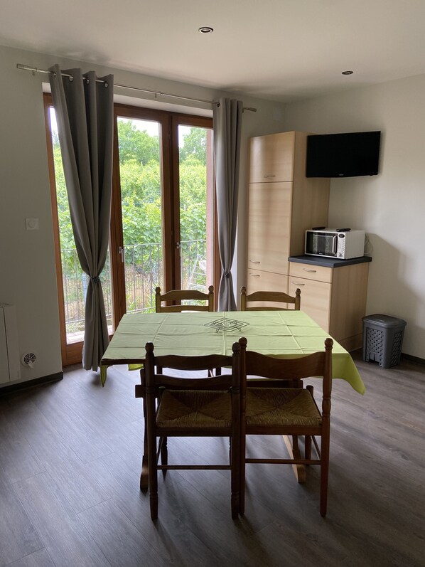 A dining area with a table, chairs, a microwave, and a TV. - Apartment Pinot 4 persons (Beblenheim)