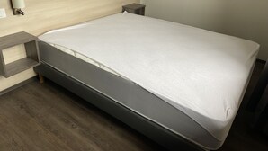 A modern hotel room with a wooden headboard, a white mattress, and a grey storage bench. - Apartment Pinot 4 persons (Beblenheim)