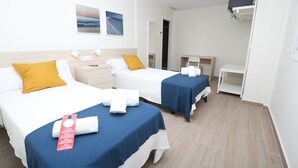 Una habitación de hotel con dos camas, un escritorio, una silla y un armario.