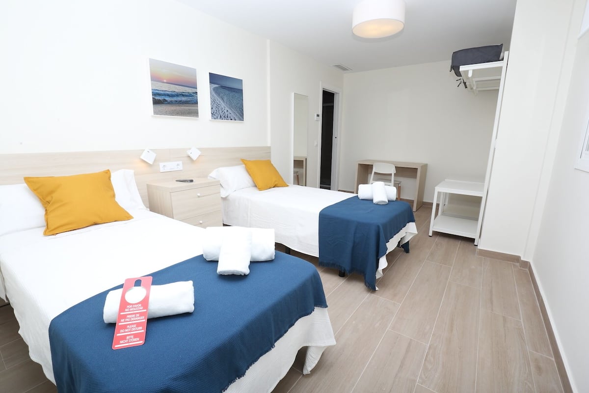 Ett hotellrum med två sängar, ett skrivbord, en stol och en garderob.