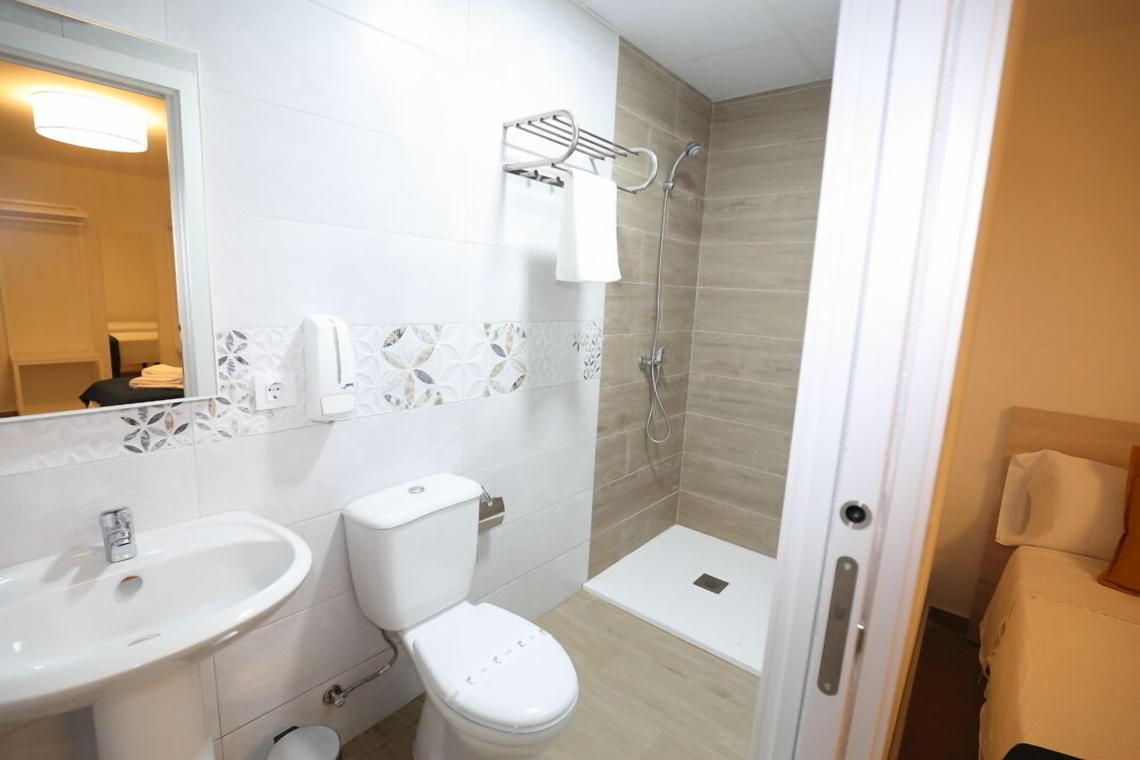 Une salle de bain avec un lavabo, des toilettes et une douche, le tout de couleur blanche.