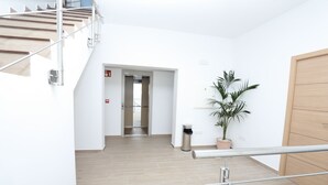 Un interior moderno con una escalera de madera, una planta en maceta y una puerta.
