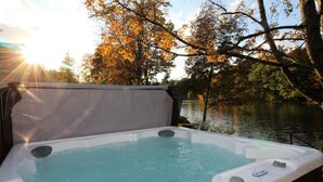 A hot tub with a view of a lake and autumn trees. - Avon Lakeshore - Waterfront retreat with hot tub! (Maryland)
