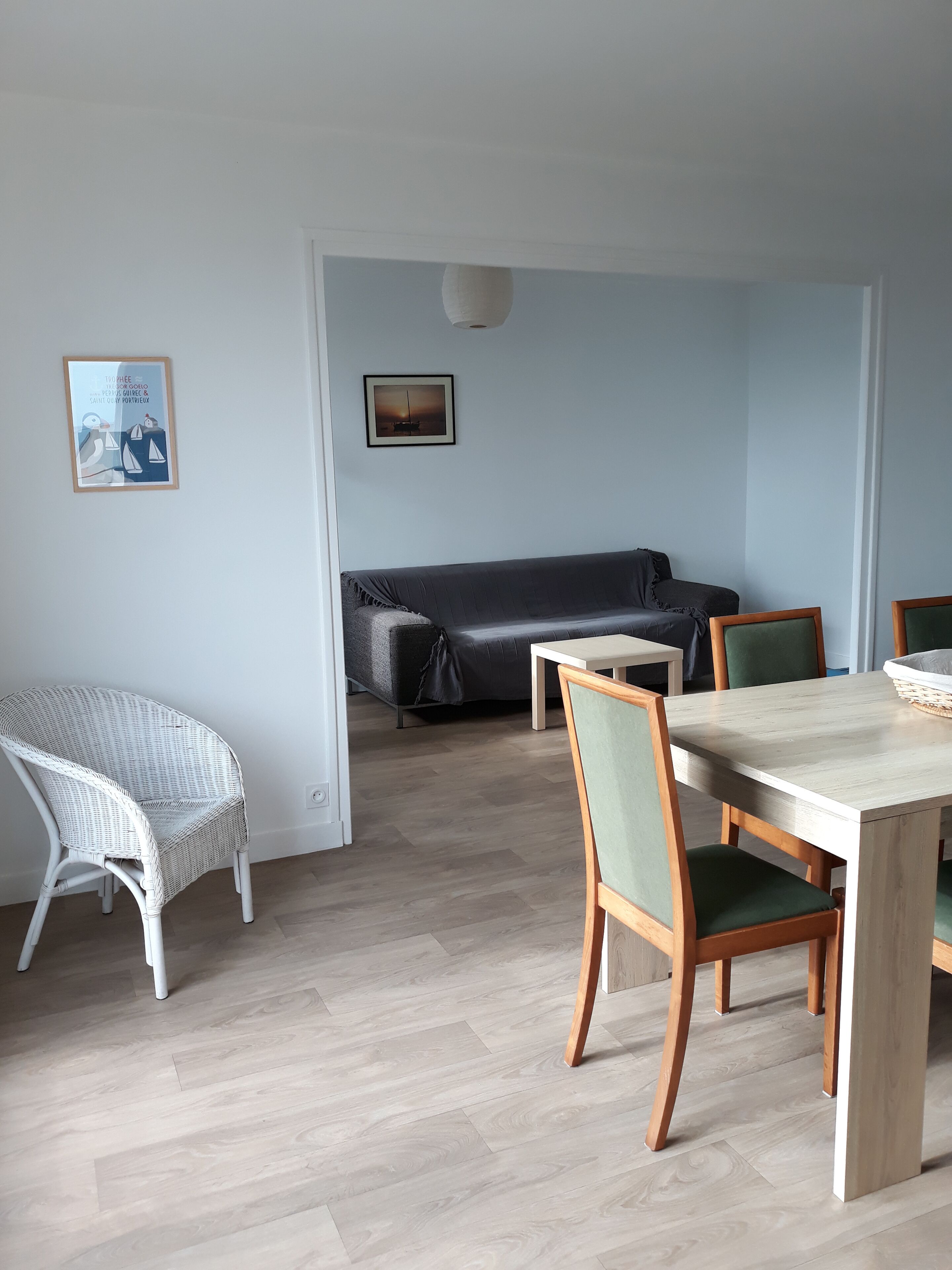 Habitació amb taula de dinar, cadires, un sofà i dues quadres al mur.