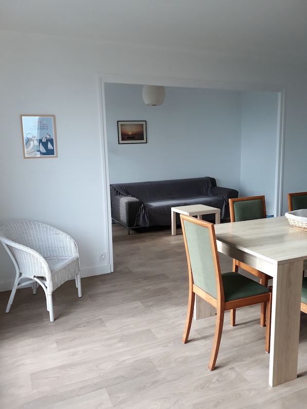 Une pièce comprenant une table à manger, des chaises, un canapé et deux tableaux encadrés accrochés au mur.
