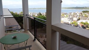 A balcony with a green table and chairs, overlooking a coastal town and the sea. - Apartment with panoramic sea view over the bay of Perros Guirec (Perros Guirec)
