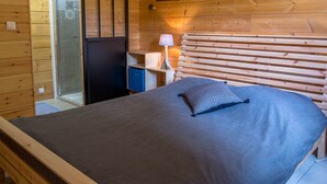 A wooden cabin room with a bed, a small desk with a lamp, and a wardrobe. - Chalet 6 people, Gérardmer, Les Bas-Rupts (Gérardmer)