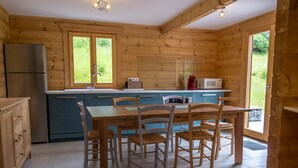 A wooden cabin kitchen with a dining table, chairs, a refrigerator, a sink, and a window. - Chalet 6 people, Gérardmer, Les Bas-Rupts (Gérardmer)
