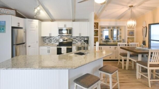 A modern kitchen with white cabinetry, a granite island, and a dining area with wooden chairs. - Short walk to the beach * Montego Bay;Ocean City, MD (Ocean City)