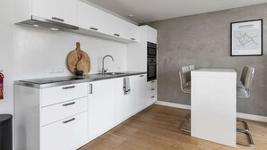 A modern kitchen with white cabinets, a wooden cutting board, a sink, and a stove. - Luxurious rooftop penthouse with rooftop terrace, a balcony, bath, duo shower (Groningen)