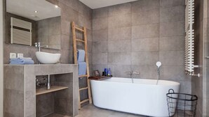 A modern bathroom with a freestanding bathtub, a wooden ladder, a towel rack, and a metal basket. - Luxurious rooftop penthouse with rooftop terrace, a balcony, bath, duo shower (Groningen)